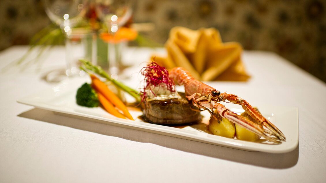 Ein kunstvoll angerichteter Teller mit Meeresfrüchten, Gemüse und Beilagen. Der Tisch ist elegant gedeckt und schafft eine ansprechende Atmosphäre. | © Jürgen Fuchs