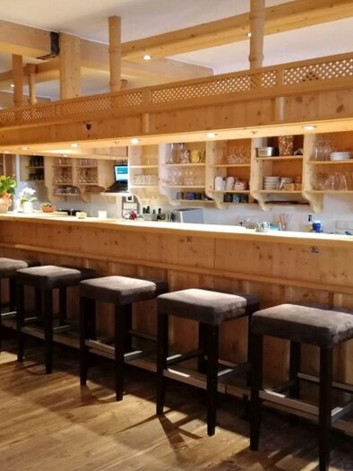 A cozy bar with wooden interiors and high chairs. The space is bright and friendly, ideal for relaxed gatherings. | © Bernd Lichtenauer