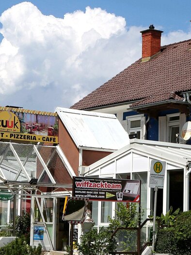 Ein Restaurant mit dem Namen "Cuk" bietet Pizzeria und Café an. Die Fassade ist bunt gestrichen und der Himmel ist wolkig. | © TV Region Graz - Lunghammer