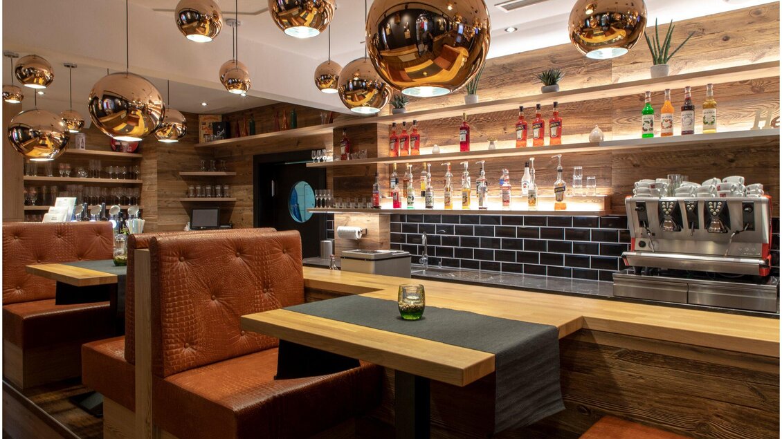 Ein modernes Restaurant mit Holzverkleidung und stilvollen, runden Lampen. Die Bar ist gut bestückt und einladend gestaltet. | © Region Graz - Lunghammer