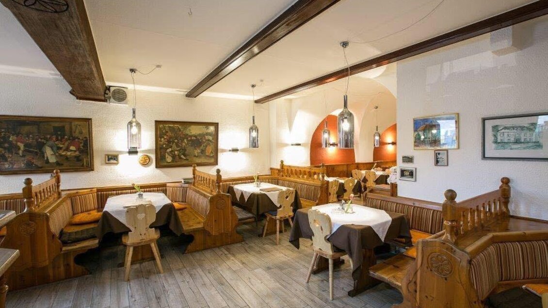 Ein gemütliches Restaurant mit Holzmöbeln und warmem Ambiente. Die Tische sind festlich gedeckt und es hängt Kunst an den Wänden. | © Klaus Morgenstern