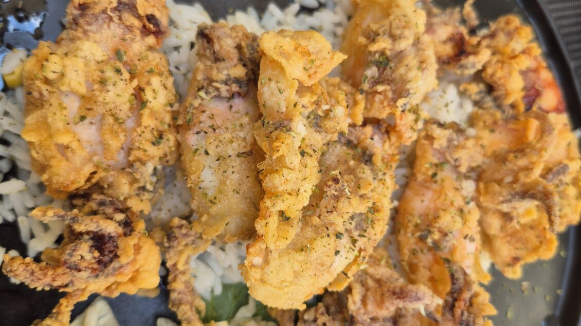 Ein Teller mit gebratenem Hähnchen auf Reis, garniert mit Salat und einer Tomatenscheibe. Das Gericht ist knusprig und appetitlich angerichtet. | © TV Hochsteiermark