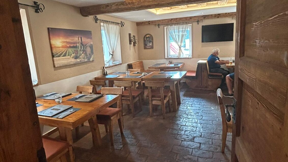 Ein gemütliches Restaurant mit Holzmobiliar und warmem Licht. Tische sind für Gäste vorbereitet, und eine malerische Landschaft ist an der Wand zu sehen. | © TV Hochsteiermark