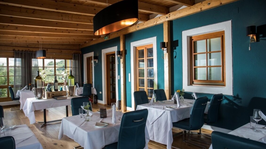 Ein modernes Restaurant mit hellblauen Wänden und stilvollen Holzmöbeln. Die Tische sind elegant gedeckt und strahlen eine einladende Atmosphäre aus. | © Sattler