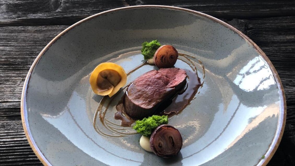 Ein elegantes Gericht auf einem Teller, das zartes Fleisch, zarte Pilze und grüne Garnitur zeigt. Die Anrichtung ist stilvoll und ansprechend. | © Sattler