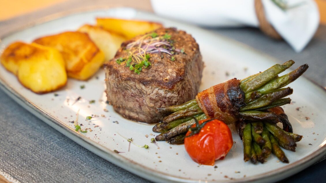 Steak mit Bratkartoffeln, Speckbohnen und Tomate auf einem Teller im Restaurant Schachenwald | © Schachenwald - Wolfgang Hummer