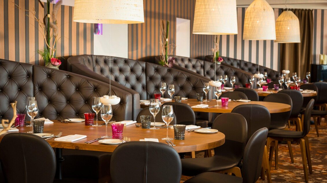 Ein elegantes Restaurant mit gemütlichen Sitzecken und stilvollen Tischen. Die warmen Farben und die moderne Beleuchtung schaffen eine einladende Atmosphäre. | © Restaurant Schlossberg - Werner Krug