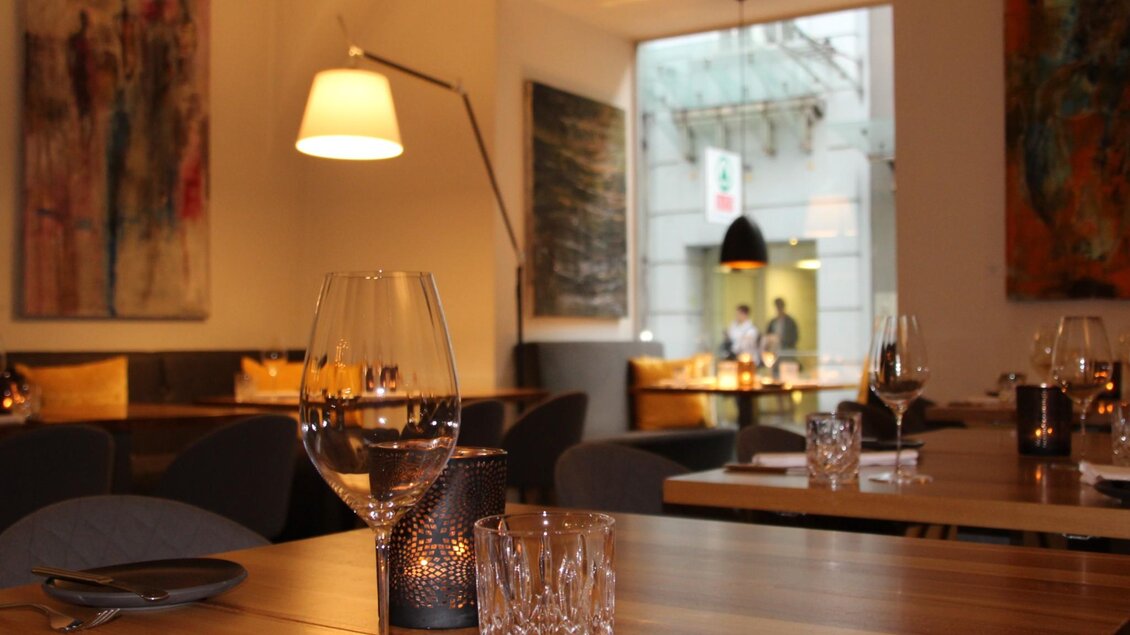 Ein modernes Restaurant mit eleganten Tischen und stilvoller Dekoration. Große Fenster lassen natürliches Licht herein und schaffen eine einladende Atmosphäre. | © Schmidhofer im Palais