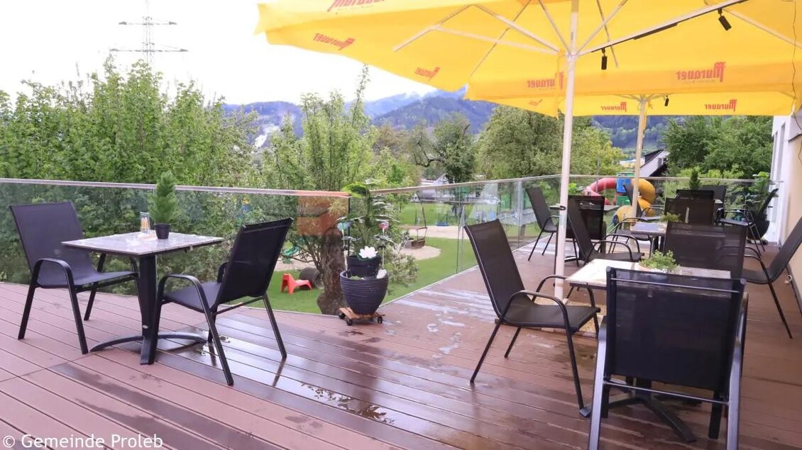 Eine gemütliche Terrasse mit Tischen und Stühlen, umgeben von grünen Pflanzen. Gelbe Sonnenschirme spenden Schatten an einem entspannten Ort. | © Gemeinde Proleb