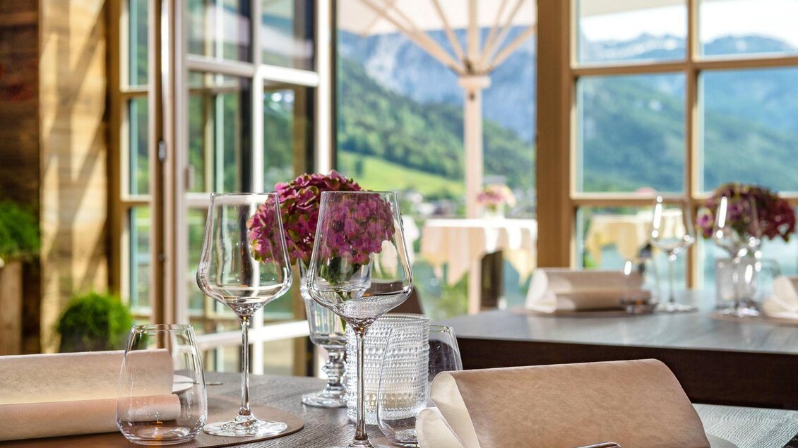 Ein elegantes Restaurant mit einem Blick auf die Berge. Der Tisch ist schön gedeckt mit Gläsern und Blumen. | © Mondi Resort