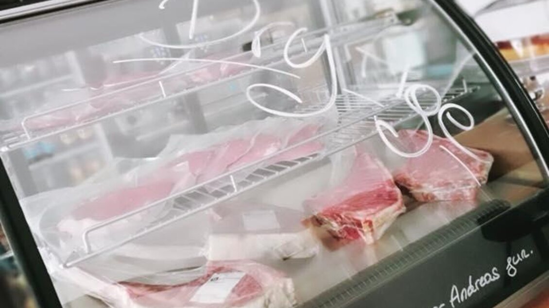 Eine eleganter Verkaufsstand mit Fleischsorten hinter einer Glasscheibe. Die Schrift darauf weist auf spezielle Angebote hin. | © Walter.Grill.Burger