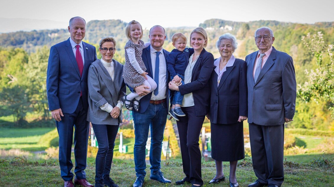Eine Gruppe von acht Personen steht im Freien vor einer malerischen Landschaft. Die Anwesenden lächeln und scheinen eine familiäre Zusammenkunft zu genießen. | © Werbelechner