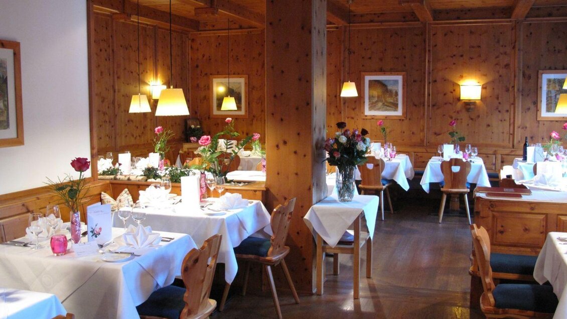 Ein Paar toastet an einem Tisch im Freien vor einem Restaurant. Die Umgebung ist grün und einladend, mit Blick auf ein Hotelgebäude im Hintergrund. | © SPA Hotel Erzherzog Johann, Bad Aussee, Restaurant (c) Ralf Tornow