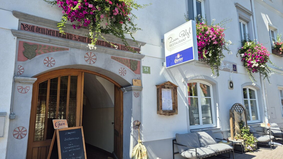 Ein Restaurant mit einem einladenden Eingang und einem Holzschild. Neben der Tür steht eine Tafel mit Menüangeboten. | © Tourismusverband Murau