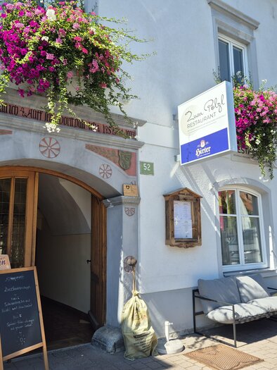 Ein Restaurant mit einem einladenden Eingang und einem Holzschild. Neben der Tür steht eine Tafel mit Menüangeboten. | © Tourismusverband Murau