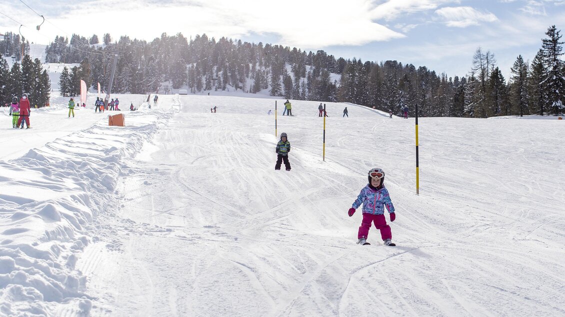 Ein verschneites Skigebiet mit Kindern, die Ski fahren. Im Hintergrund sind Bäume und eine klare, sonnige Himmel zu sehen. | © Murtal Seilbahnen Betriebs GmbH