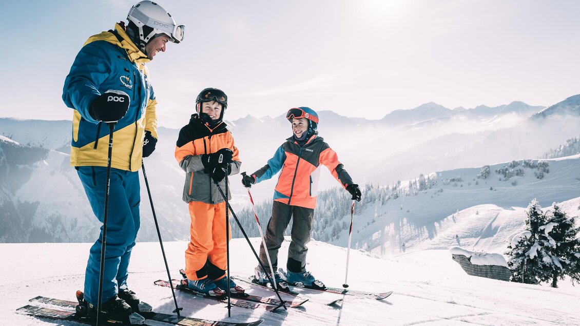 Eine Gruppe von Skifahrern steht auf einer verschneiten Piste. Die Sonne scheint und die Berge sind im Hintergrund zu sehen. | © Armin Walcher