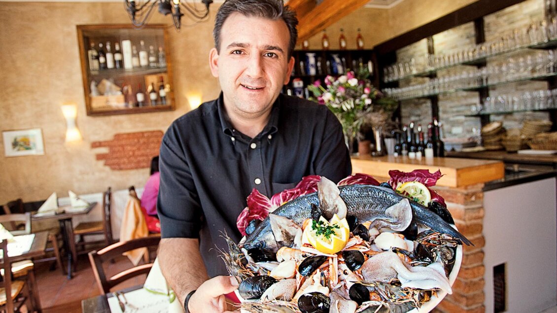 Kellner im La Tavernetta Graz hält eine Platte mit frischen Meeresfrüchten im Restaurant. | © La Tavernetta