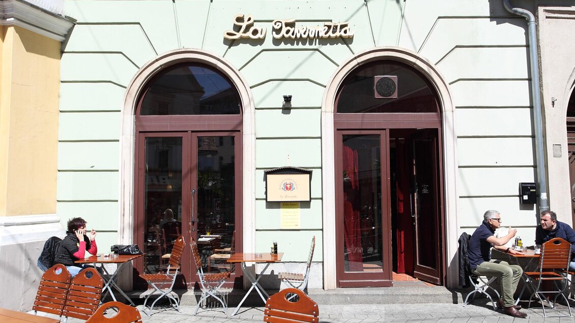 Außenbereich des La Tavernetta Graz mit Gästen an Holztischen vor der Restaurantfassade. | © Graz Tourismus - Max Wegscheidler