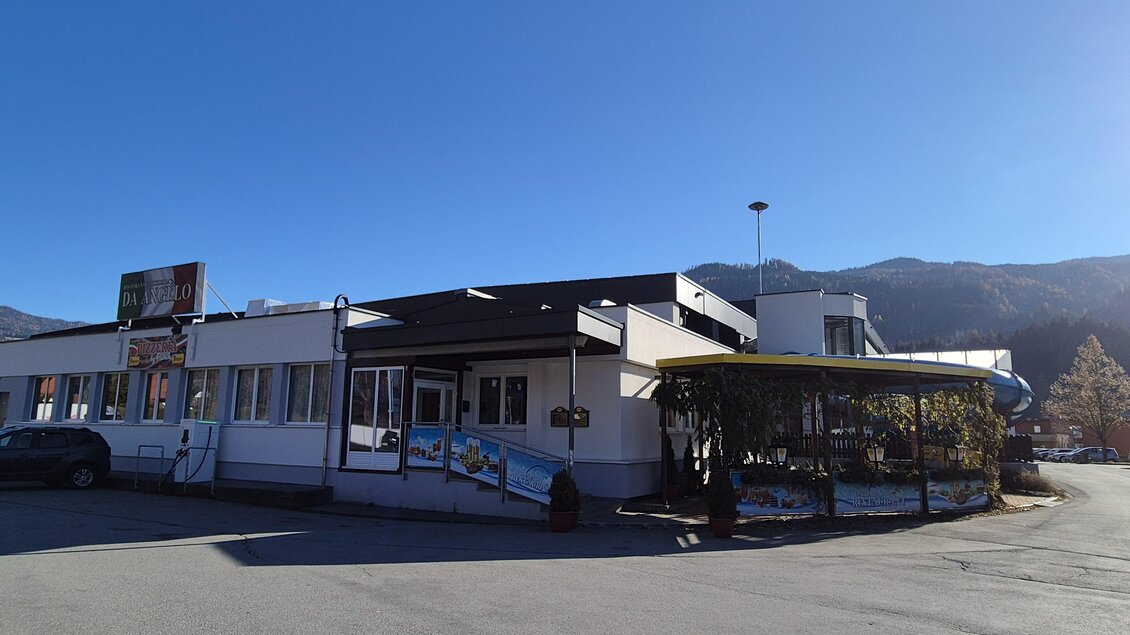 Ein modernes Gebäude mit verschiedener Architektur und einem begrünten Eingang. Im Hintergrund sind Berge unter einem klaren, blauen Himmel sichtbar. | © Tourismusverband Murau