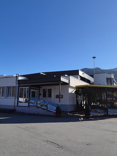A modern building with diverse architecture and a greened entrance. In the background, mountains are visible under a clear, blue sky. | © Tourismusverband Murau