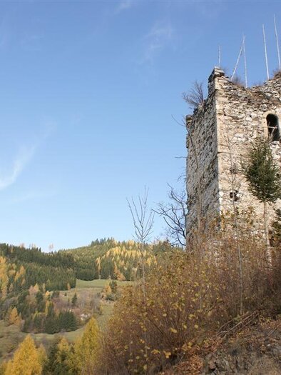 An old ruin stands on a hill, surrounded by colorful autumn forest. The clear sky complements the serene landscape. | © Ruine Offenburg
