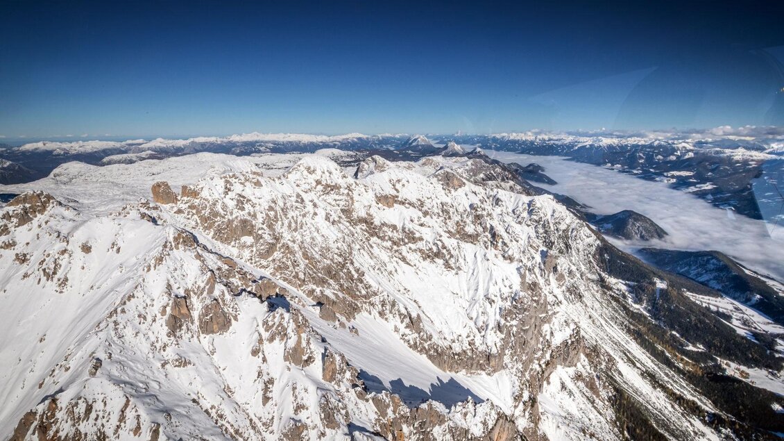 Eine beeindruckende Berglandschaft mit schneebedeckten Gipfeln und klarem Himmel. In der Ferne sind weitere Berge sichtbar, die eine majestätische Kulisse bieten.