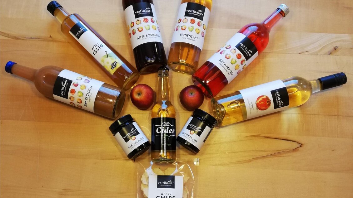 Eine Anordnung von Flaschen mit verschiedenen Getränken und Apfelchips auf einem Holzuntergrund. Die Flaschen zeigen verschiedene Sorten von Fruchtsäften und Cider. | © Markus Putz