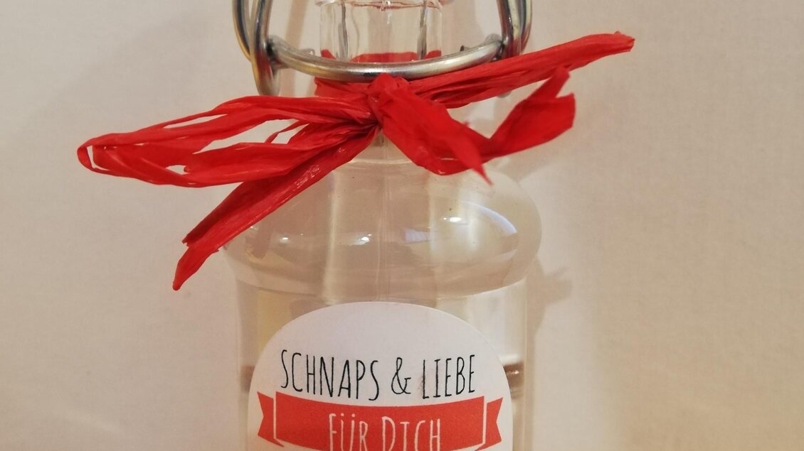Eine Flasche Schnaps mit einem roten Band verziert. Auf dem Etikett steht „Schnaps & Liebe für dich“ und der Inhalt ist Kirschbrand. | © Markus Putz