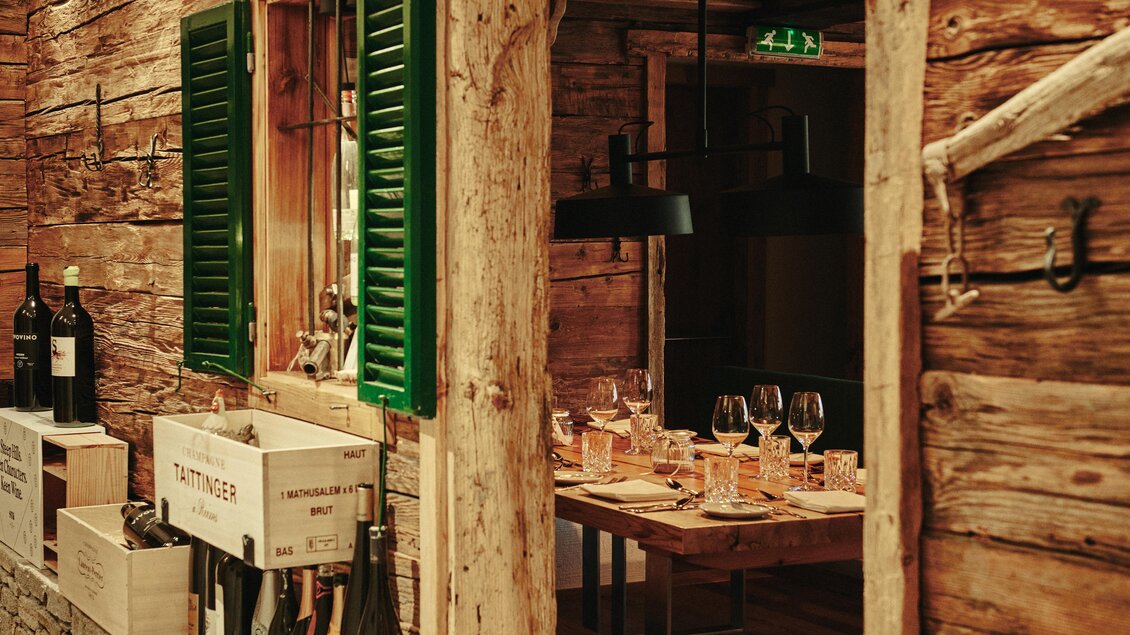 Ein rustikales Restaurant mit Holzwänden und grünen Fensterläden. Der Tisch ist für eine gemütliche Mahlzeit gedeckt. | © Felix Werinos