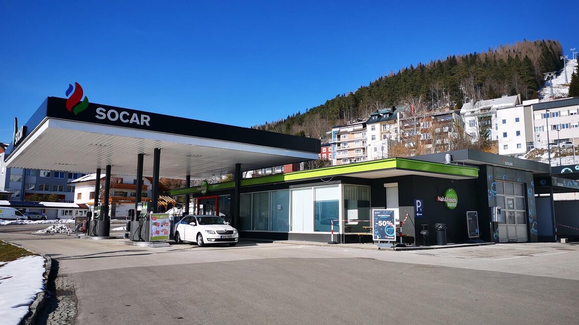 Eine moderne Tankstelle mit dem Logo von SOCAR. Im Hintergrund sind Wohnhäuser und bewaldete Hügel sichtbar. | © TV Hochsteiermark / Brigitte Digruber