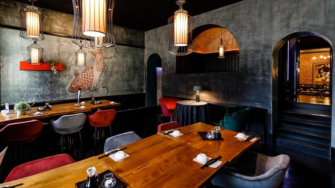 Ein stilvolles Restaurant mit einem modernen Interieur. Holztische und farbige Stühle schaffen eine einladende Atmosphäre. | © Sakana