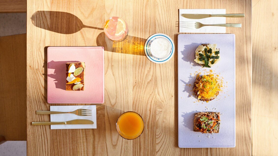 Ein schöner Tisch mit zwei Tellern, auf denen verschiedene Gerichte und ein Dessert präsentiert werden. Dazu gibt es Getränke und Besteck in eleganter Anordnung. | © Salaettl