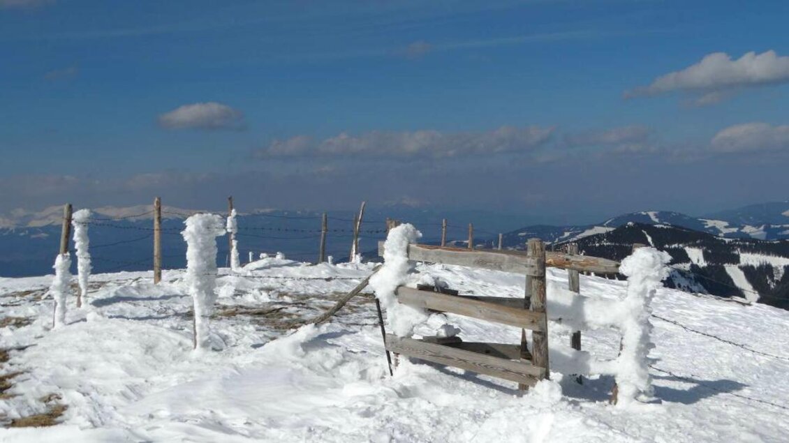Ein schneebedeckter Berggipfel mit frostbedeckten Zaunpfosten. Der Himmel ist klar und die Landschaft erstreckt sich weit in die Ferne. | © Salzstieglhaus