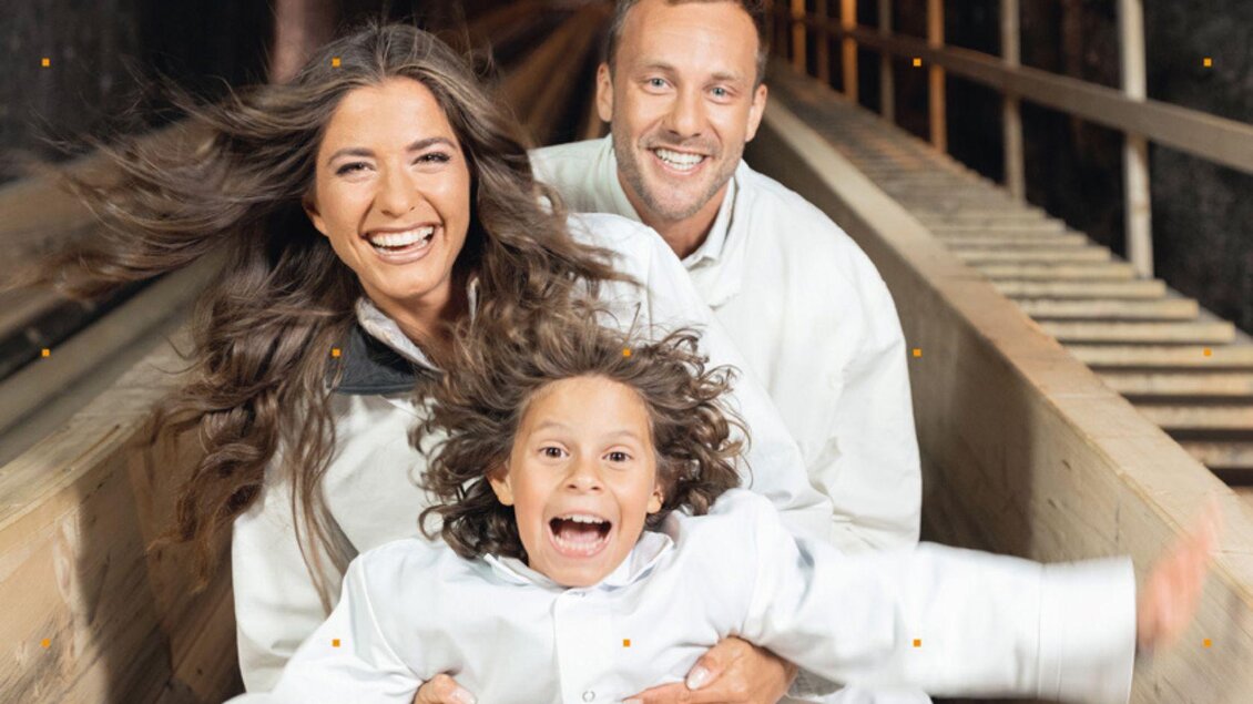 Eine fröhliche Familie sitzt in einer Achterbahn und genießt die Fahrt. Sie lachen zusammen und haben viel Spaß. | © Salzwelten