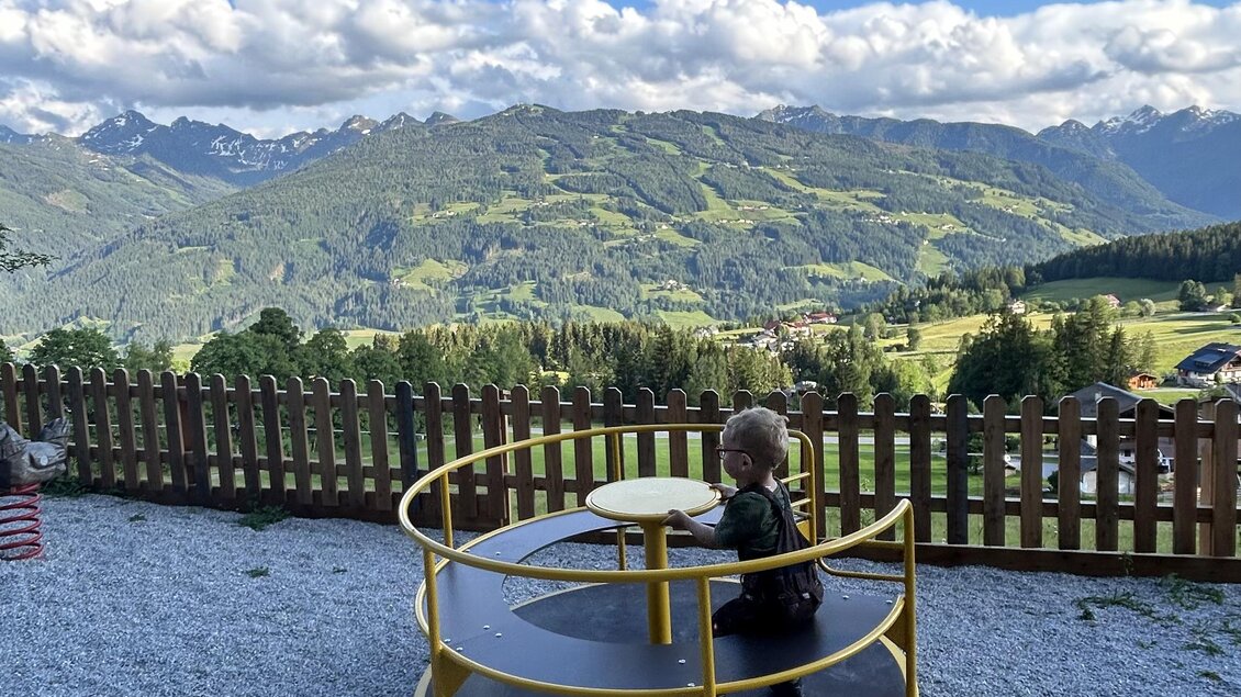 Blick auf den Spielplatz der Sattelberghütte bei blauem Himmel und Panoramablick auf die Schladminger Tauern | © Sattelberghütte