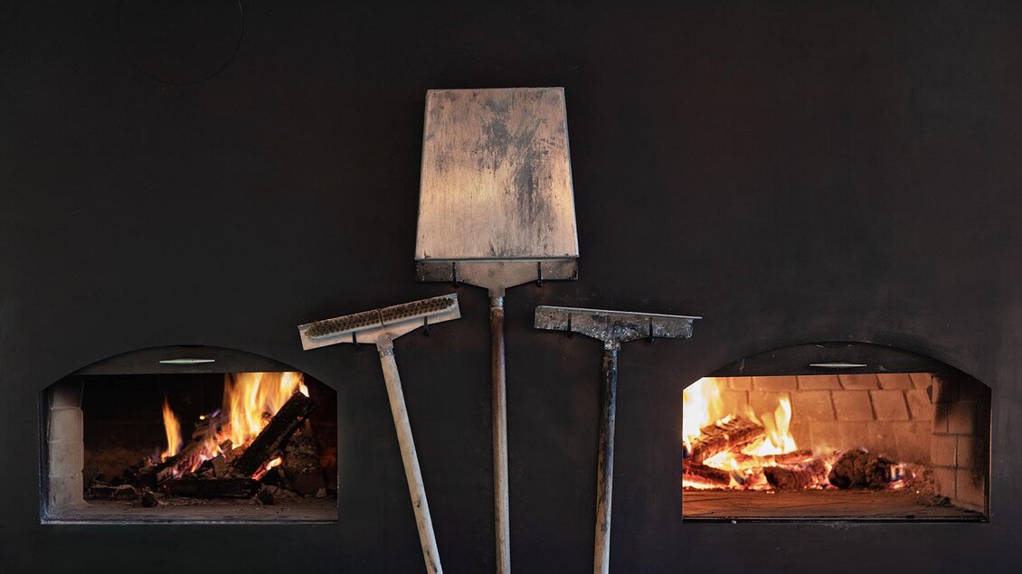 Ein moderner Kamin mit zwei Feuerstellen. Dazu stehen einige traditionelle Werkzeuge zum Schüren des Feuers. | © Restaurant Steirereck/Cathrine Stukhard