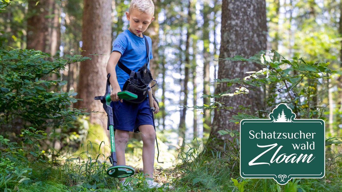 Ein Junge sucht mit einem Metall detector im Wald. Umgeben von Bäumen und Grün, erkundet er die Natur. | © www.zloam.at