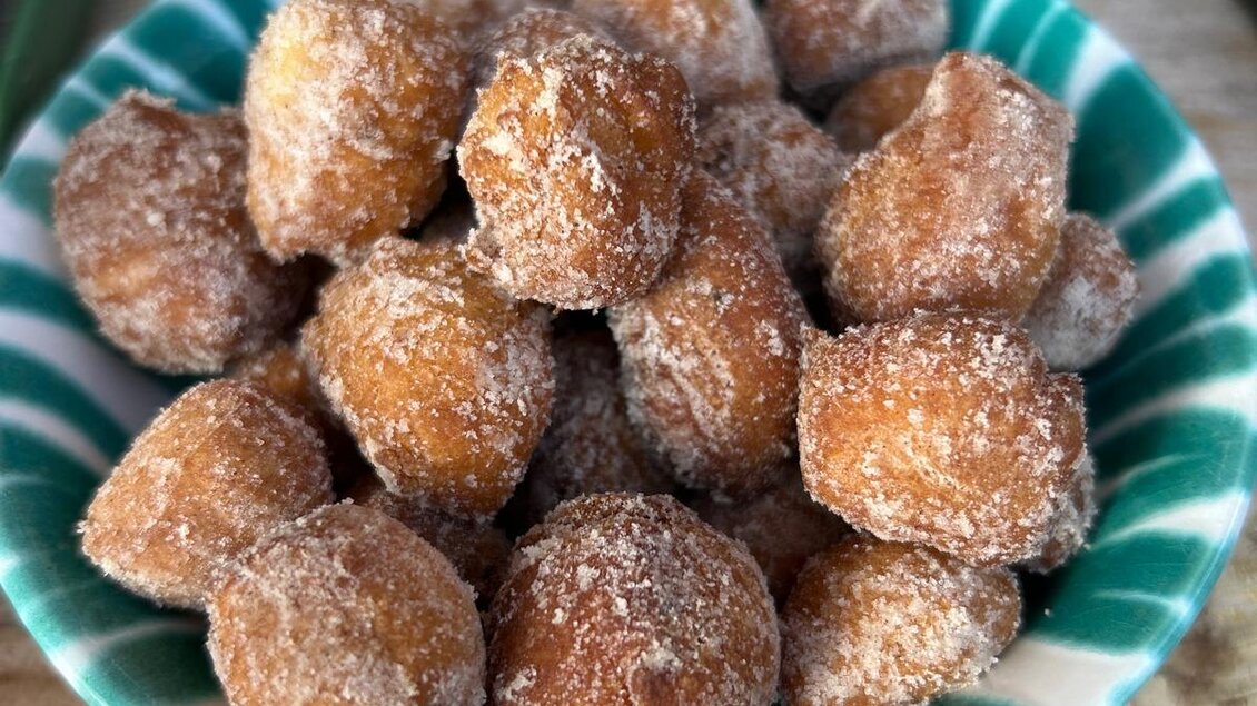 Eine Schüssel mit kleinen, frittierten Teigkugeln, die mit Zucker bestreut sind. Die Kugeln sind goldbraun und sehen köstlich aus. | © Schladminger Alm