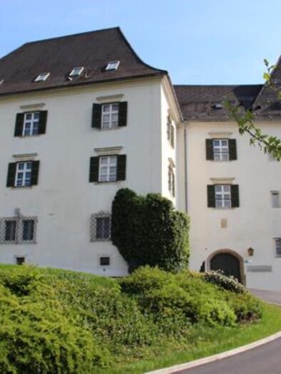A historic building with white walls and dark shutters. It is located in a green environment and has striking architecture. | © Gemeinde Wies
