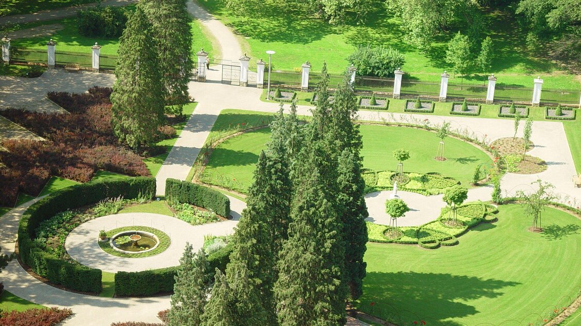 Ein schöner Garten mit gepflegten Rasenflächen und symmetrischen Blumenbeeten. Hohe Bäume und gerade Wege prägen das Bild. | © zepp@cam.at 04 | Graz Austria 