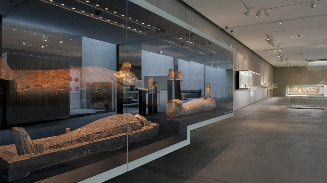 Ein modernes Museum mit Ausstellungsstücken aus der Antike ist zu sehen. Die Exponate sind hinter Glasvitrinen angeordnet und die Beleuchtung schafft eine interessante Atmosphäre. | © UMJ - N. Lackner
