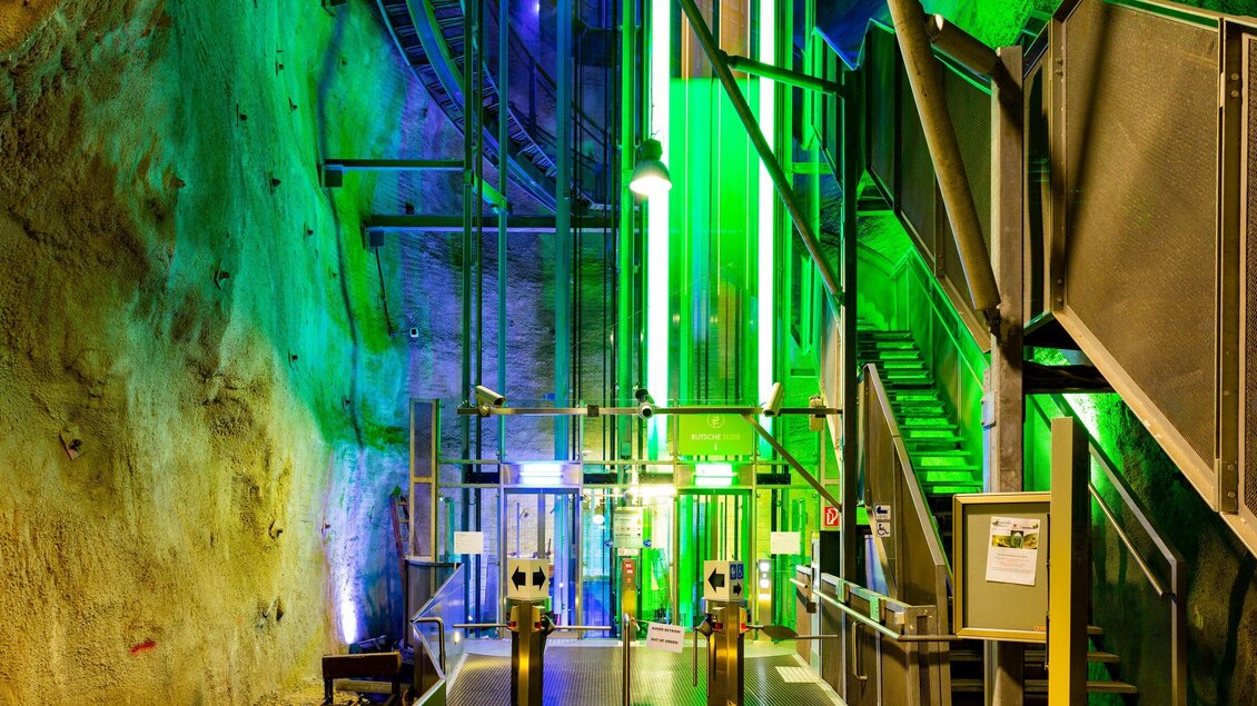 Ein moderner Aufzug in einer Höhle mit grünem Licht. Den Gästen stehen Treppen und Zugangsschalter zur Verfügung. | © Graz Tourismus - Harry Schiffer