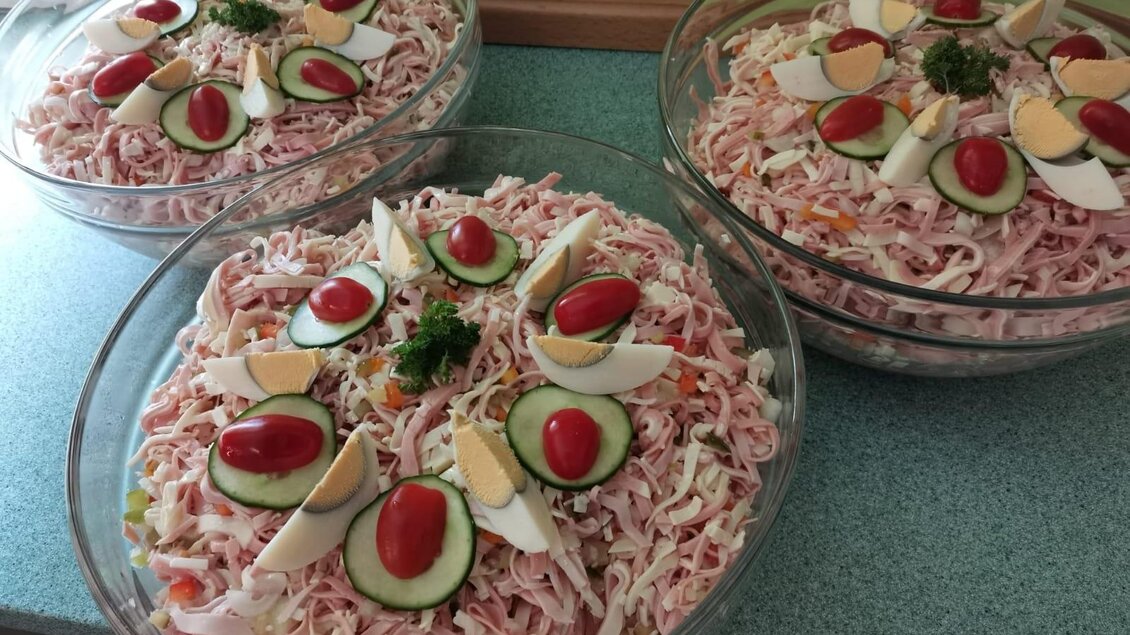 Drei große Schalen Salat mit dekorativen Zutaten. Die Salate sind mit Tomaten, Eiern und Gurken geschmückt. | © Schlosstaverne