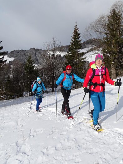 A group of people is hiking in the snowy mountains. They are wearing snowshoes and enjoying the winter landscape. | © Weges