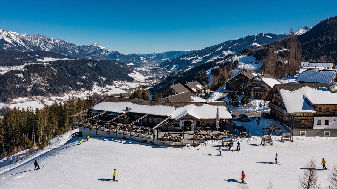 Eine schneebedeckte Landschaft mit Skifahrern und modernen Chalets. Der klare blaue Himmel sorgt für ein perfektes Winterambiente. | © Christine Höflehner