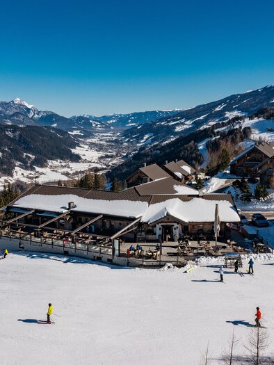 Eine schneebedeckte Landschaft mit Skifahrern und modernen Chalets. Der klare blaue Himmel sorgt für ein perfektes Winterambiente. | © Christine Höflehner