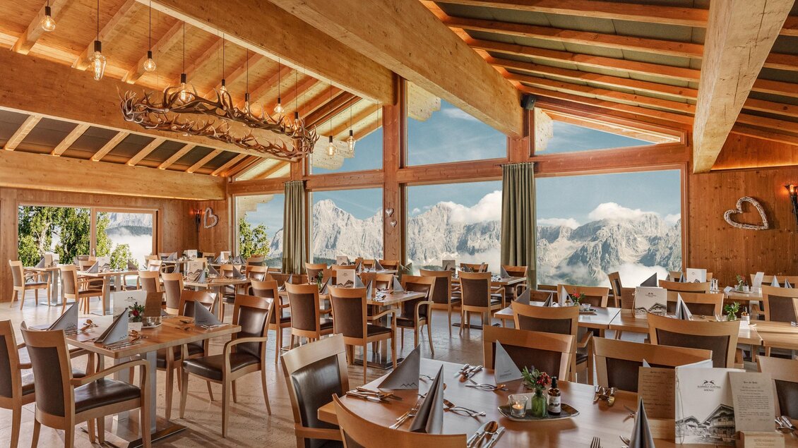 Ein elegantes Restaurant mit modernen Holzmöbeln und großen Fenstern. Im Hintergrund sind beeindruckende Berge zu sehen. | © Christine Höflehner
