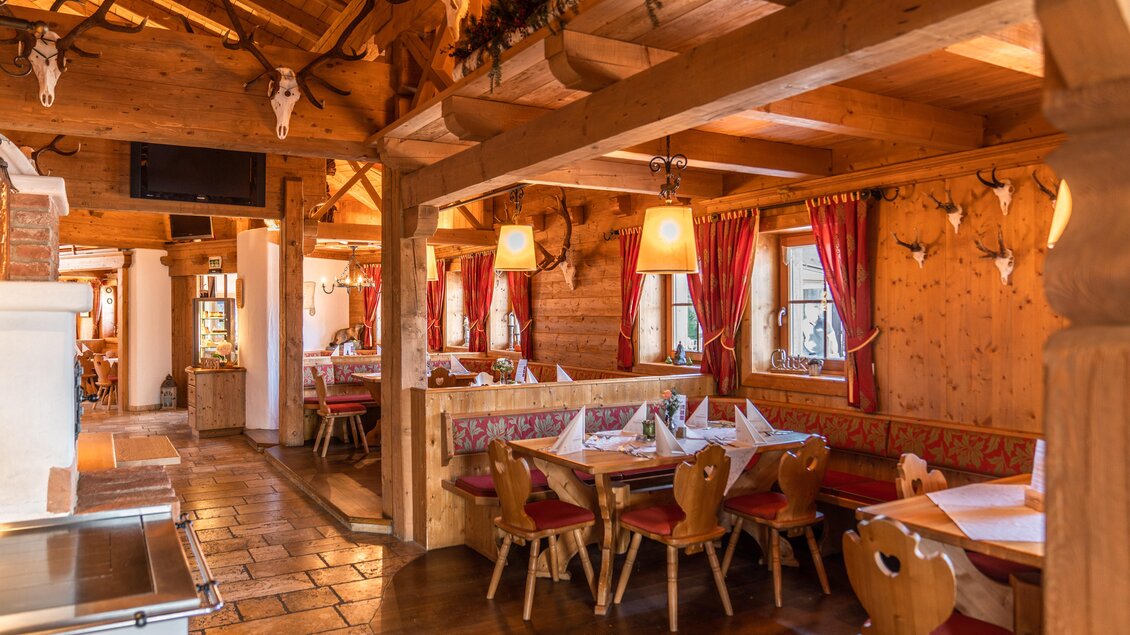 Ein rustikales Restaurant mit Holzdekor und gemütlichen Sitzbereichen. Die Wände sind mit Geweihen geschmückt und warmes Licht sorgt für eine einladende Atmosphäre. | © Christine Höfflehner