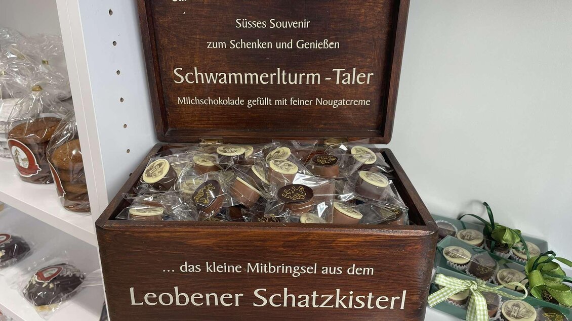 Eine Holzschachtel mit dem Aufschrift „Schwammerlturm-Taler“ voller runder Süßigkeiten aus Milchschokolade. Ideal als Souvenir zum Schenken und Genießen. | © Erzberg Leoben